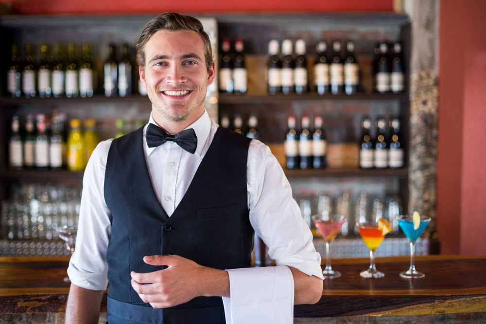 A bartender is well dressed and ready to serve drinks to customers.